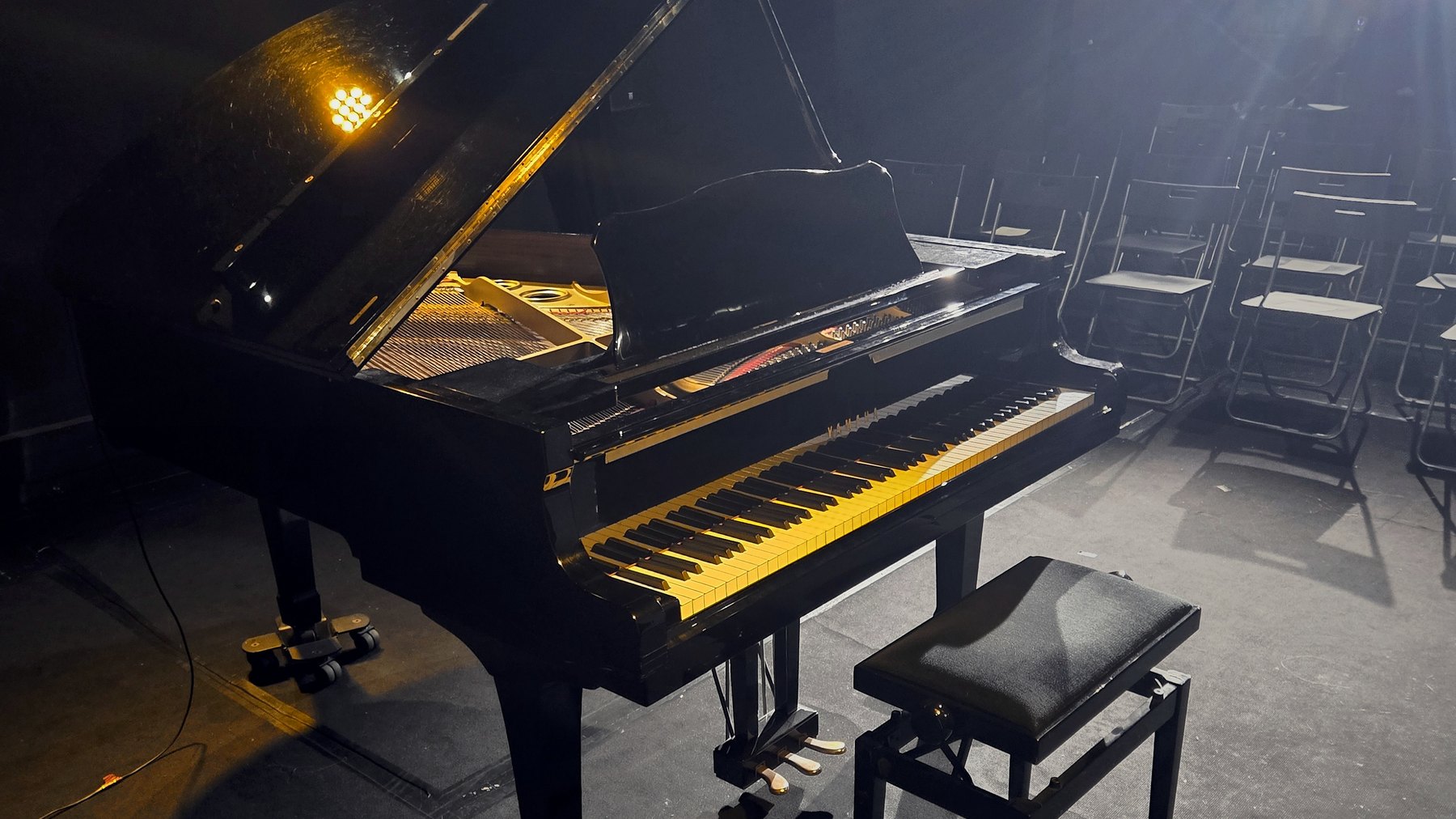 Piano de cauda iluminado em palco durante recital SoloPiano